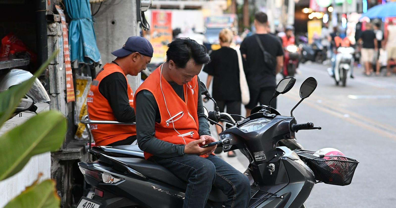 Delivery rider handing over a parcel while the customer holds a phone with a QR code